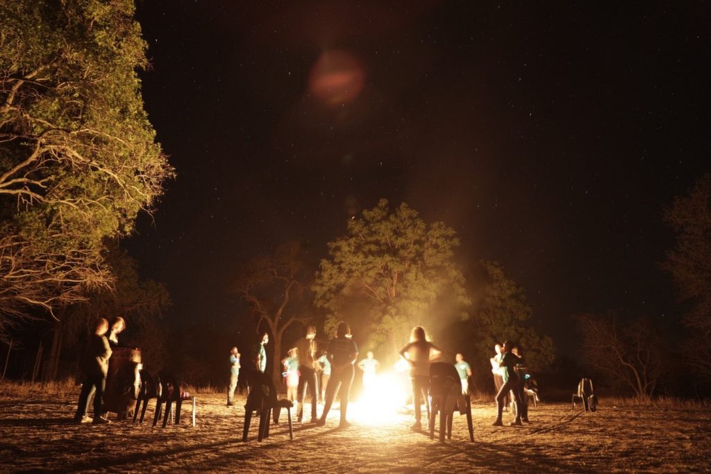 People dancing and cheering around a fire